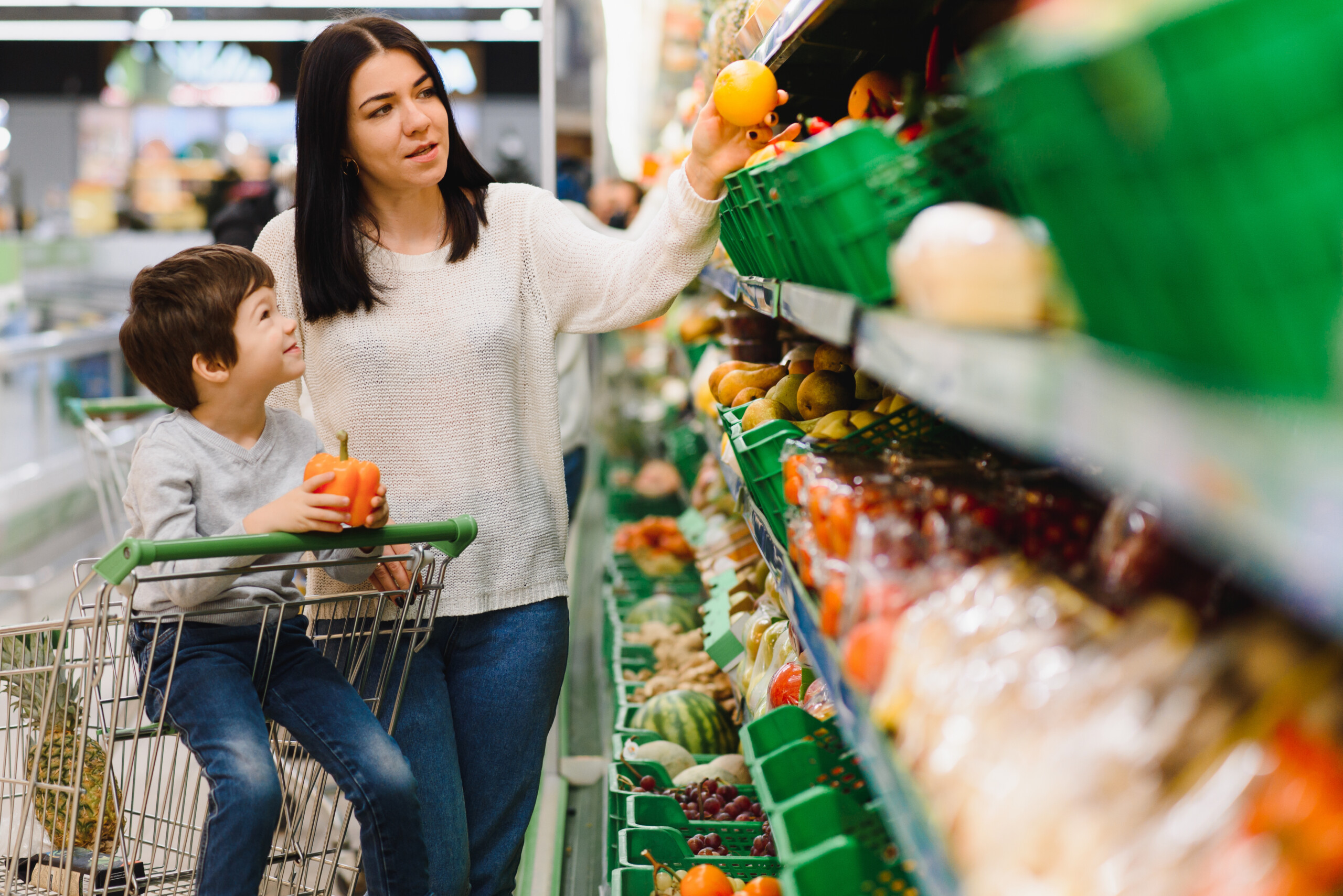 Young mother with her little baby boy at the supermarket.